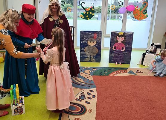 Pani dyrektor pasuje przedszkolaka na księżniczkę.