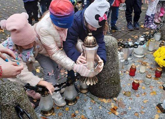 Dzieci podczas stawiania znicza na pomniku.