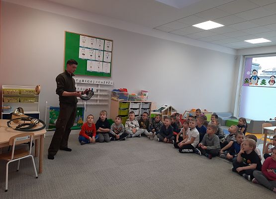 Sygnalista myśliwski pokazuje instrument grupie dzieci.