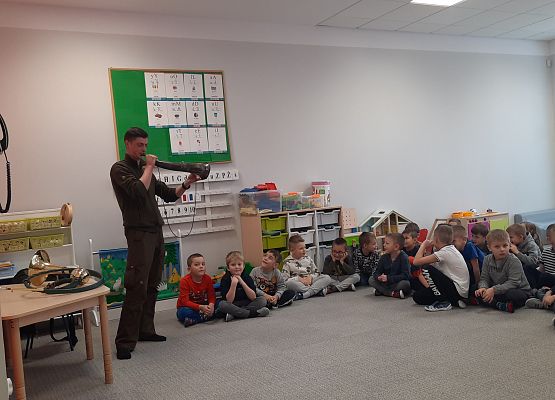 Sygnalista myśliwski pokazuje instrument grupie dzieci.