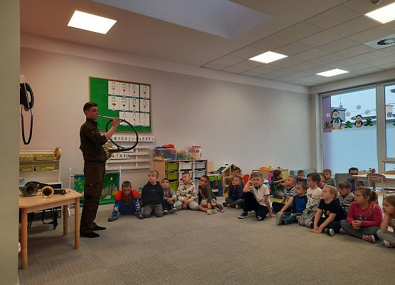 Sygnalista myśliwski pokazuje instrument grupie dzieci.