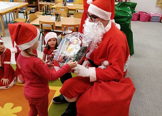Mikołaj wręcza prezent dziewczynce.