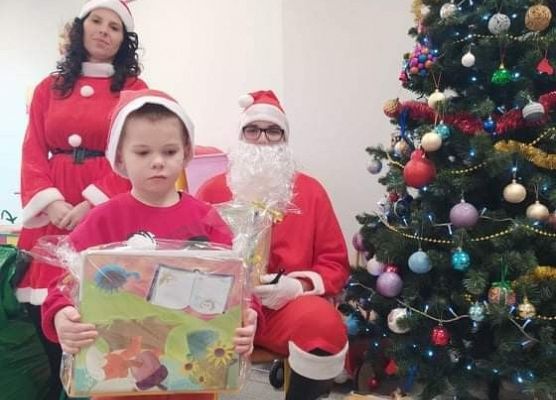 Chłopiec odbiera prezent od Mikołaja.