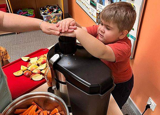 Chłopiec pomaga robić sok z warzyw i owoców.